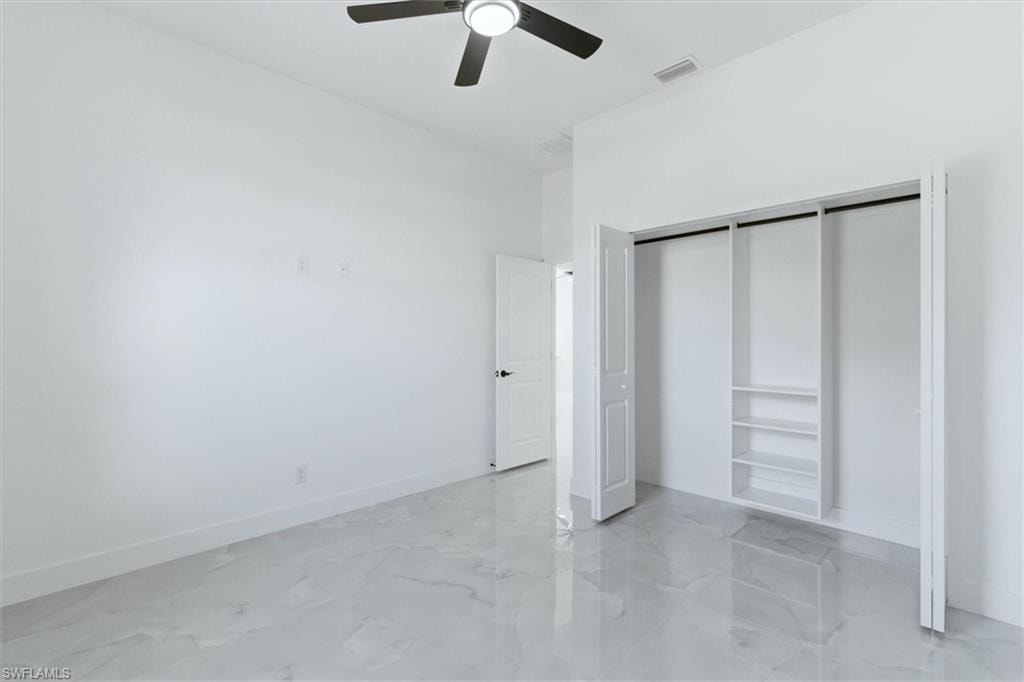 Spacious interior with marble-look flooring, ceiling fan, and built-in closet organization