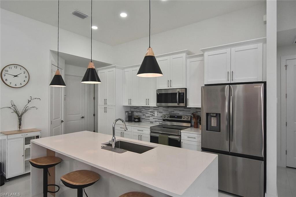 Kitchen featuring appliances with stainless steel finishes, white cabinets, a kitchen island with sink, and recessed lighting