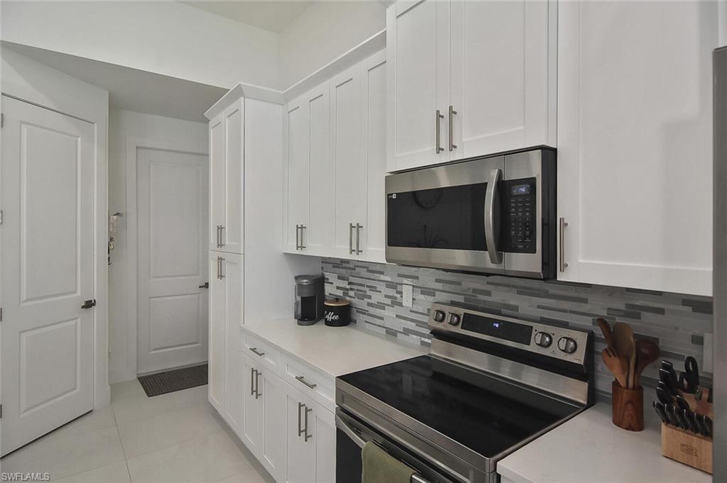 Kitchen with appliances with stainless steel finishes, white cabinets, and light tile patterned floors