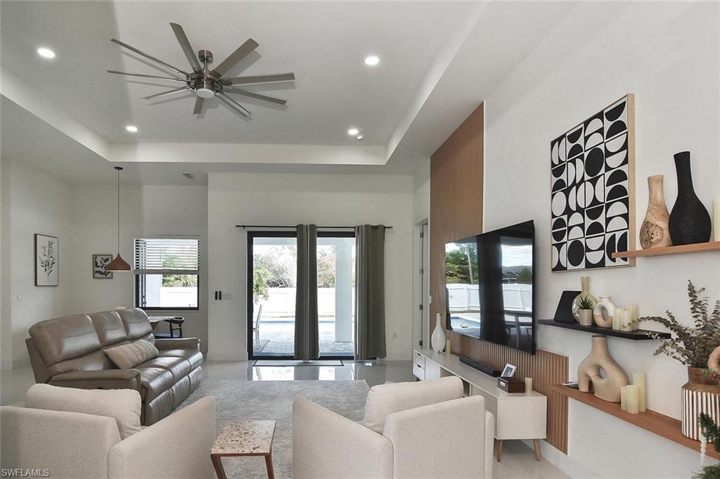Living area with a raised ceiling, a ceiling fan, a towering ceiling, and recessed lighting