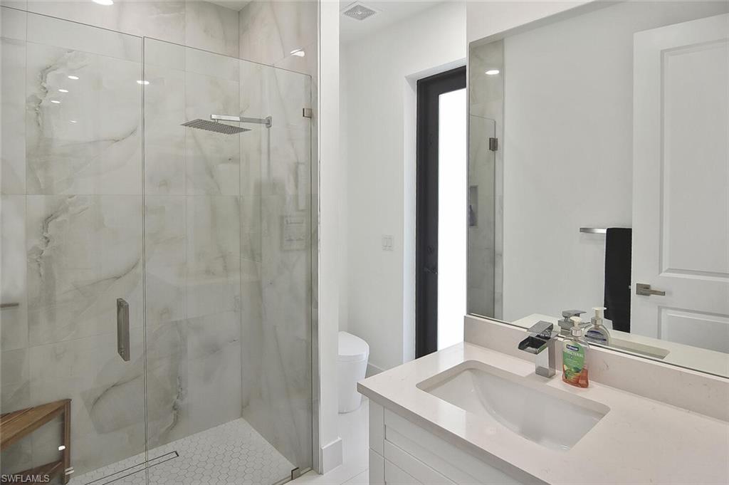 Bathroom with vanity, a marble finish shower, and recessed lighting