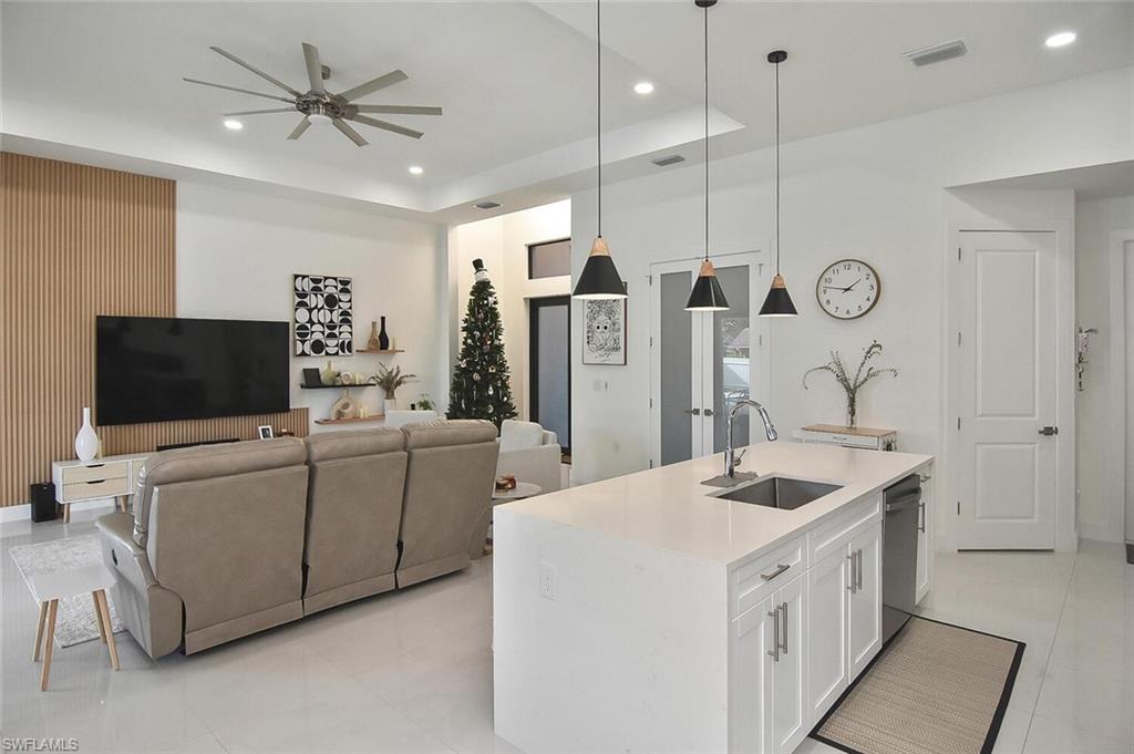 Kitchen featuring hanging light fixtures, white cabinets, recessed lighting, light stone counters, and a raised ceiling
