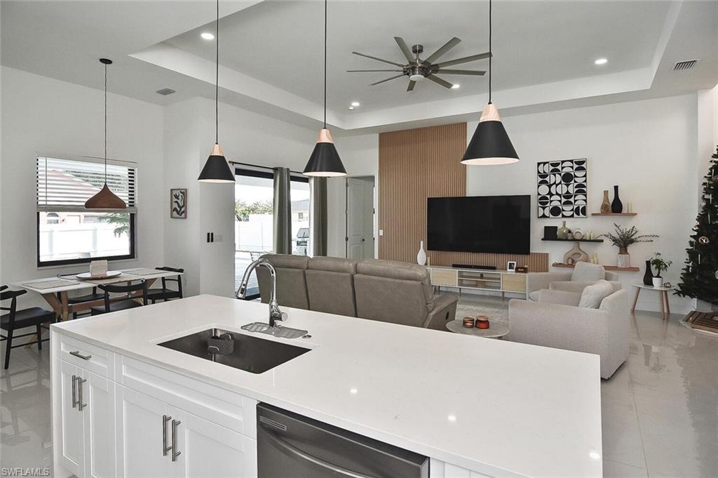 Kitchen with pendant lighting, a center island with sink, white cabinetry, stainless steel dishwasher, and recessed lighting