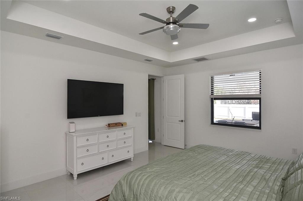 Bedroom featuring a tray ceiling, a ceiling fan, light tile patterned flooring, and recessed lighting