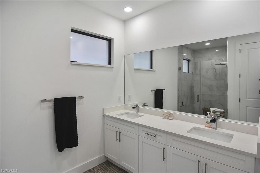 Full bath with a marble finish shower, double vanity, and recessed lighting