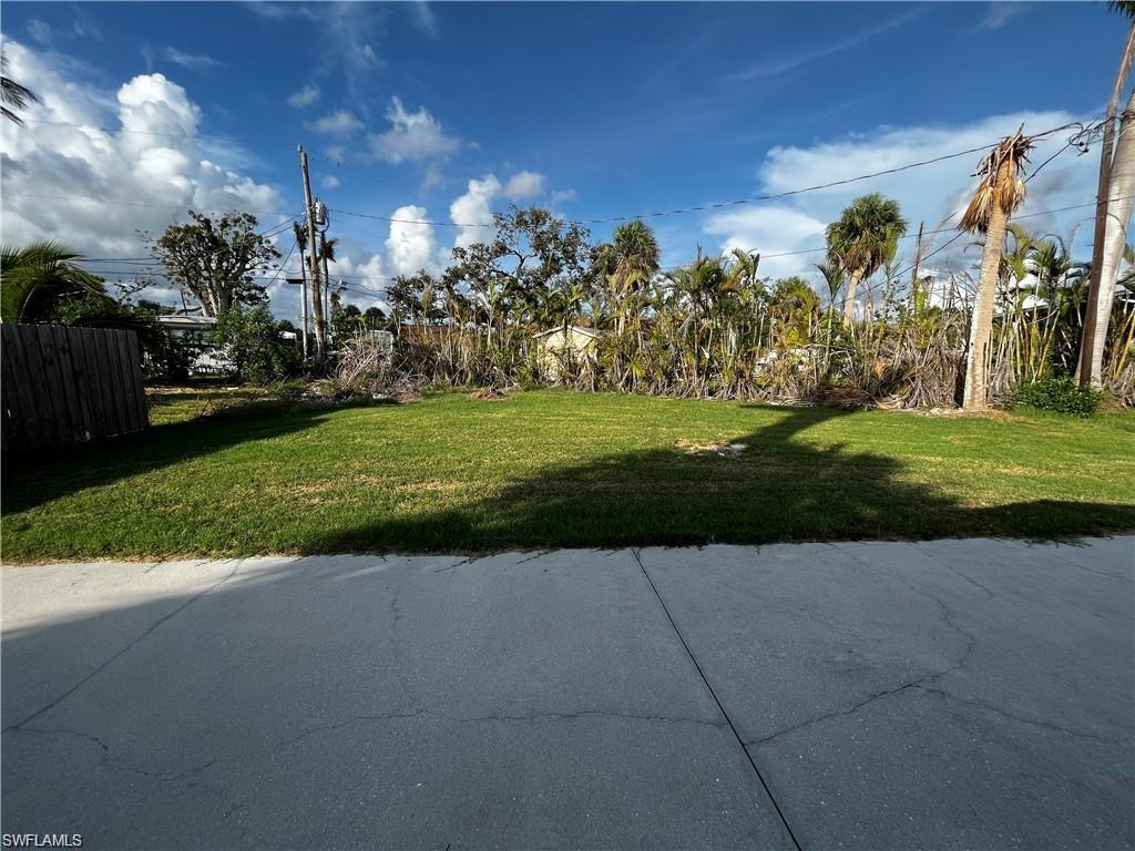 Expansive green lawn with established perimeter foliage, featuring a concrete pad