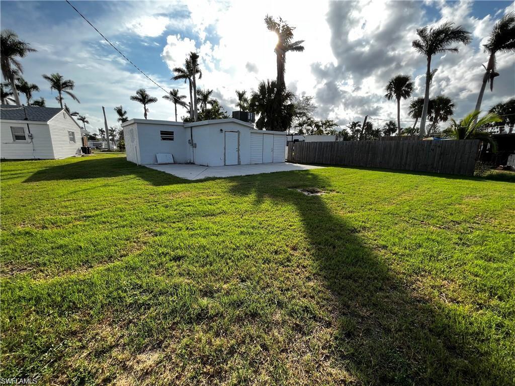 Expansive grassy yard with mature palm trees and a privacy fence