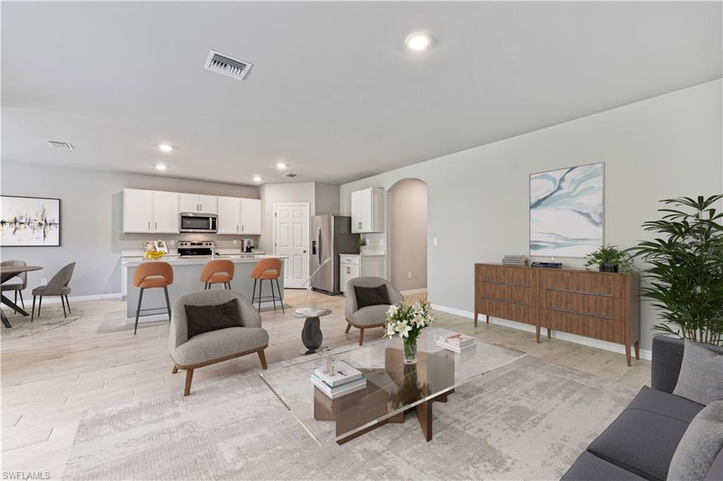 This image is virtually staged. Living area with arched walkways, light wood finished floors, and recessed lighting