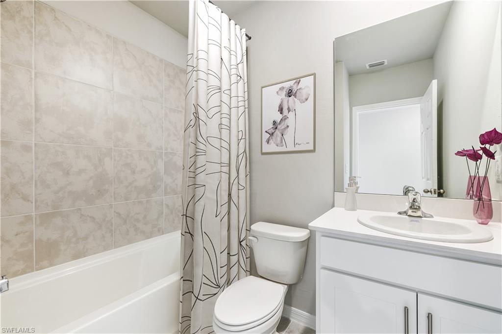 This image is virtually staged. Bathroom featuring vanity and shower / bathtub combination with curtain
