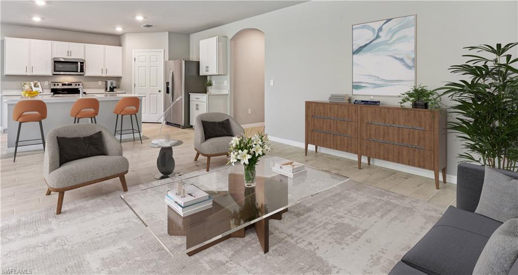 This image is virtually staged. Living area featuring arched walkways, recessed lighting, and light wood-style floors