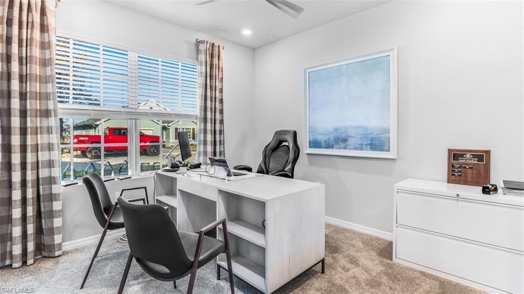 Model home. Office space featuring light carpet and ceiling fan