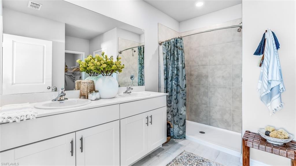 Model home. Bathroom with double vanity and a shower stall