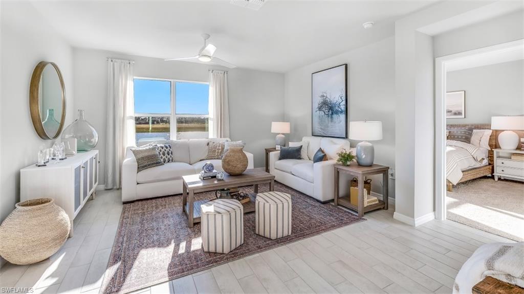Model home. Living room featuring light wood-style flooring and ceiling fan
