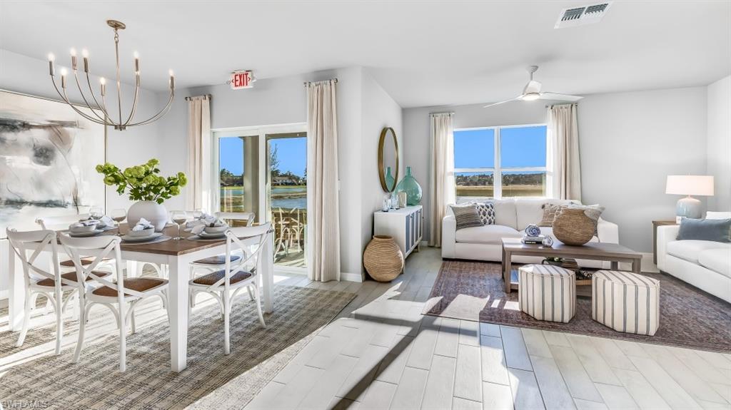 Model home. Living room with a ceiling fan, wood tiled floors, hanging lights, and a water view