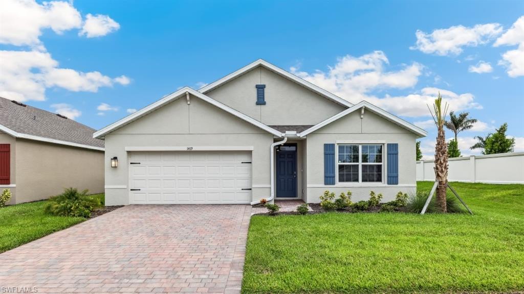 Model Home Contemporary stucco exterior featuring a two-car garage, brick paver driveway, mature landscaping, and a vibrant blue entry door with coordinating shutters
