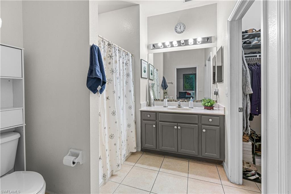 Dual vanity with undermount sinks, tile flooring, and a walk-in closet