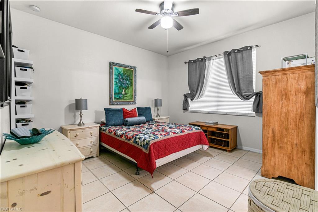 Tile flooring throughout, a window with horizontal blinds, and a ceiling fan with integrated lighting