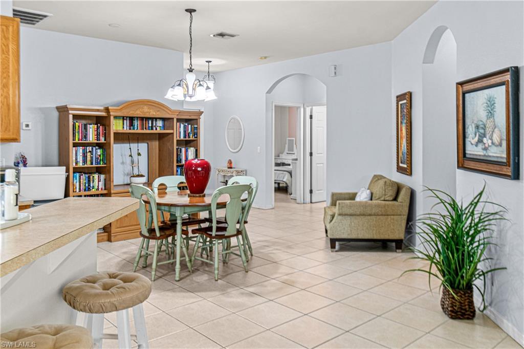 Tile flooring throughout, arched doorways, a built-in entertainment center, and a breakfast bar