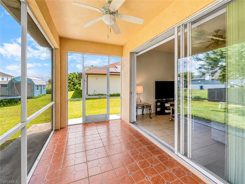 Screened-in patio with patterned tile flooring, a ceiling fan, and sliding glass doors