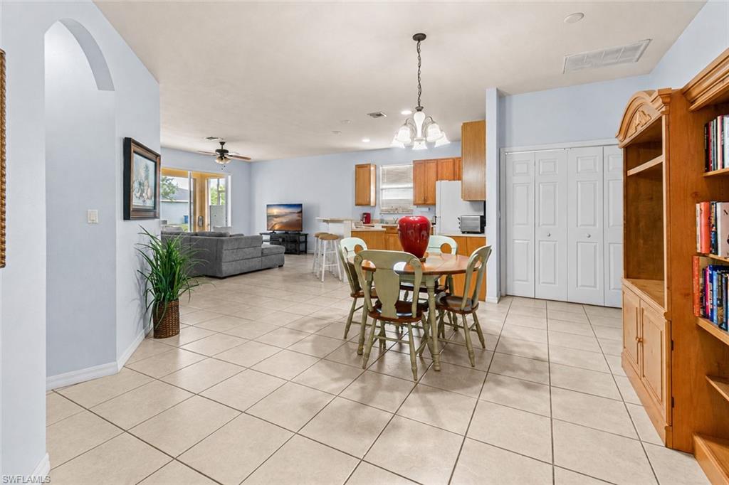 Arched entryway, neutral-toned tile flooring, built-in shelving, wood cabinetry, and white bi-fold closet doors