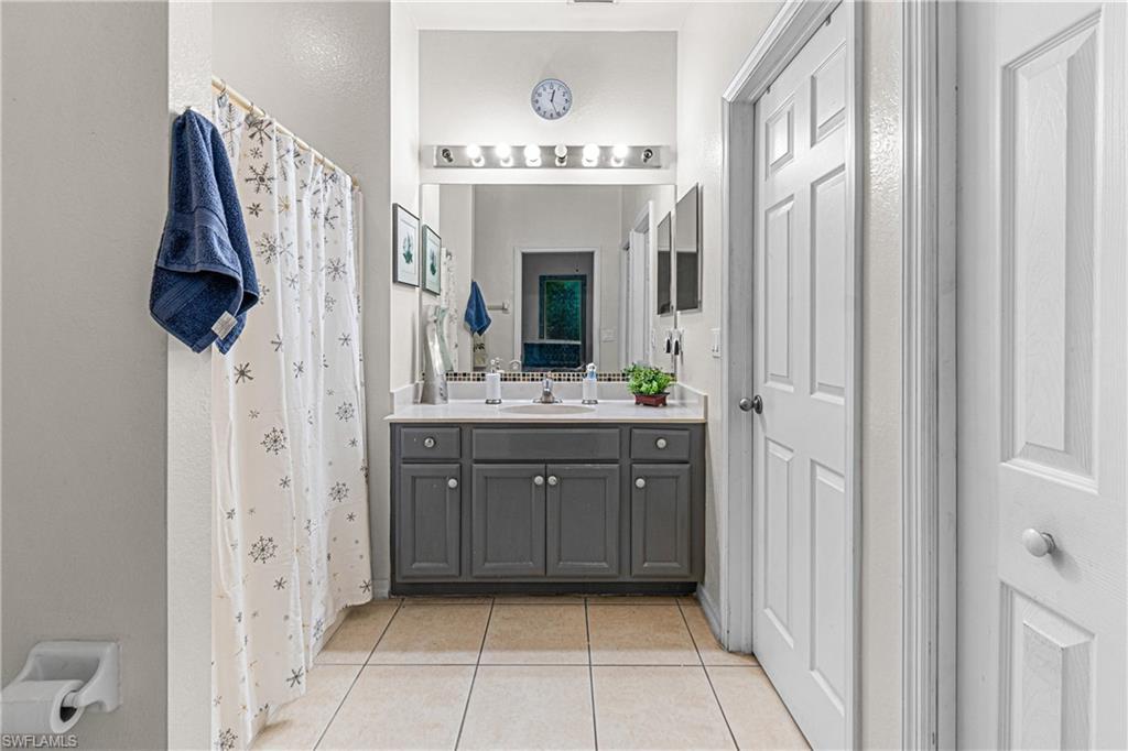Dual vanity with gray cabinetry, white countertop, and tile flooring