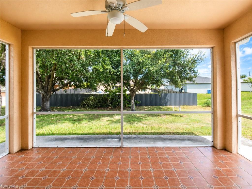 Screened patio featuring a ceiling fan, terracotta-toned floor tiles, and a mature tree backdrop