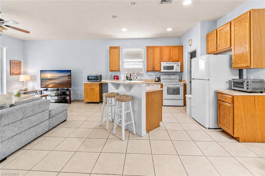 Kitchen featuring wood cabinetry, white appliances, and a breakfast bar