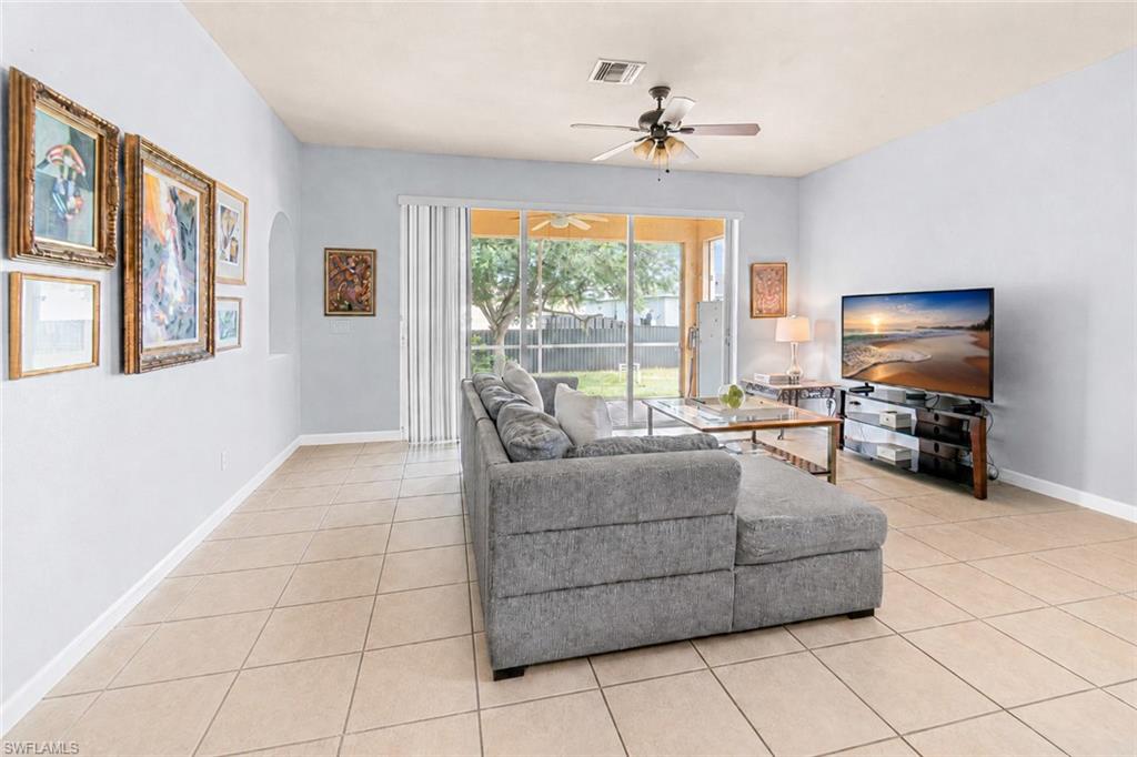 Tile flooring, recessed archway, ceiling fan, sliding glass doors, and a covered patio