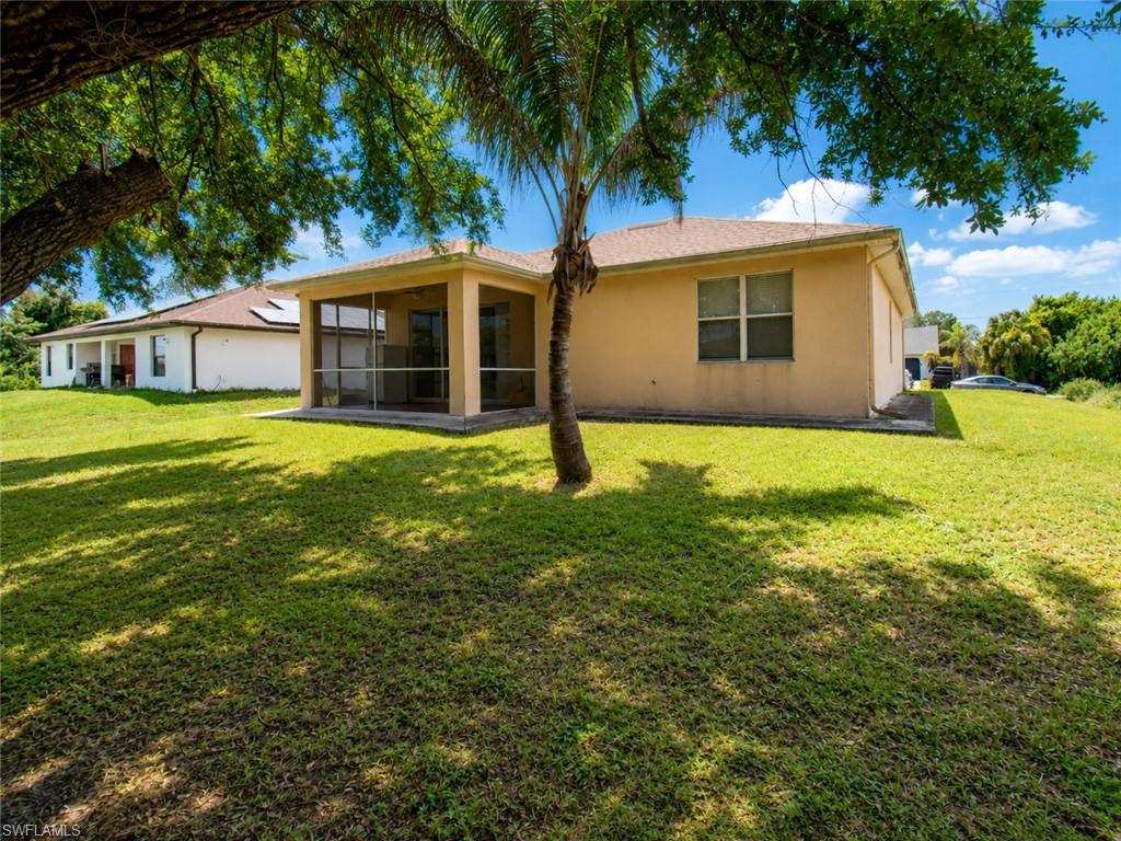 Expansive grass lawn with mature trees and a screened-in patio