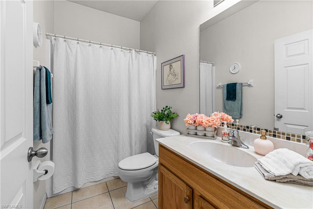 Single vanity with an integrated sink, wood-finish cabinetry, and a mosaic tile backsplash