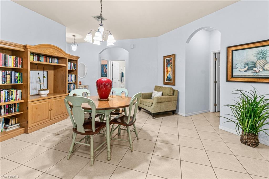 Built-in wood-finish cabinetry with shelving, tiled flooring, arched doorways, and a chandelier lighting fixture