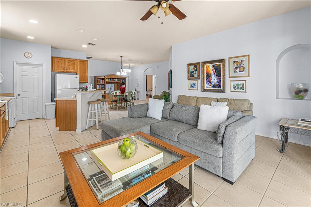 Open concept living area featuring tile flooring, a kitchen island with seating, recessed lighting, and a ceiling fan
